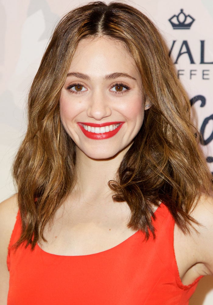 Emmy Rossum wore a tangerine soft-sheen cocktail dress balanced by a reserved scoop-neck bodice