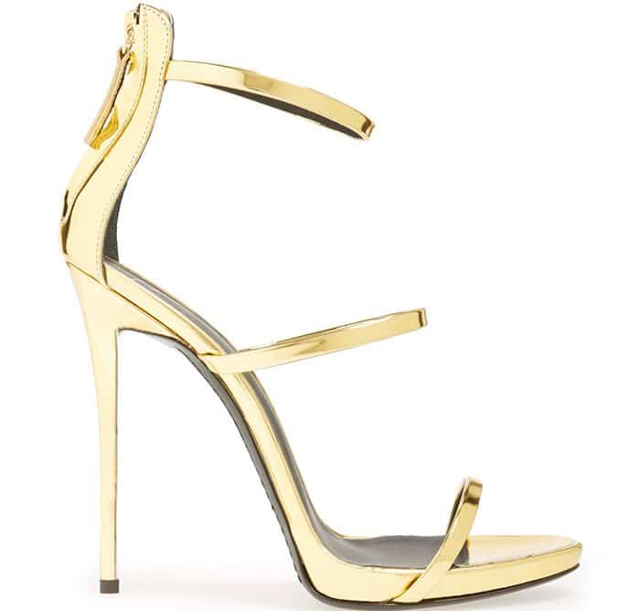 Slender goldtone straps highlight a sophisticated pointy-toe sandal set on a slim stiletto heel