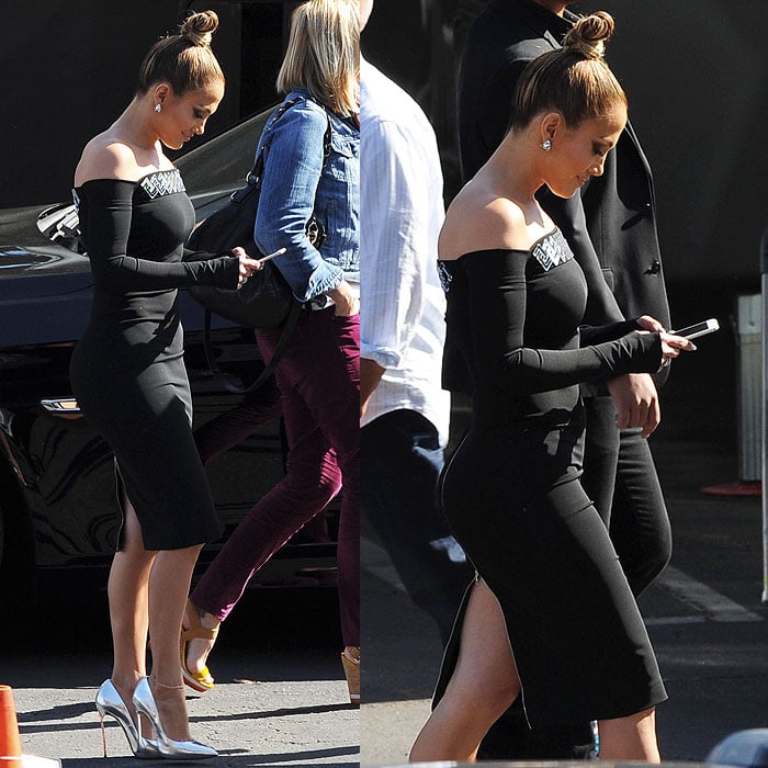 Jennifer Lopez busy texting on her phone and not realizing that the back zipper on her dress has fully opened
