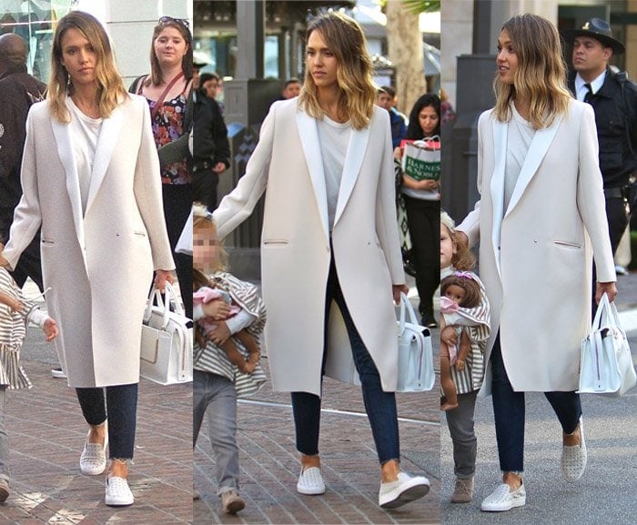 Jessica Alba looks effortlessly stylish in a long white coat paired with a casual white tee and jeans, complemented by chic sneakers for a relaxed yet polished look