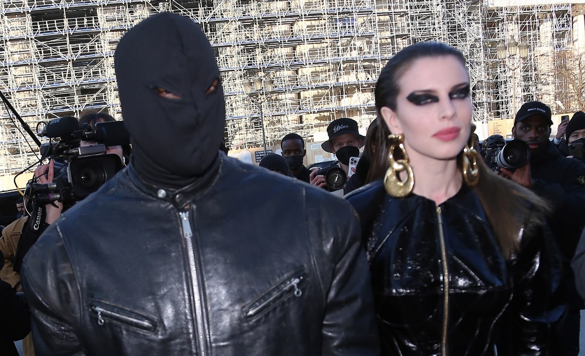 Kanye West covers his face with a head mask while his girlfriend Julia Fox wears dramatic eye makeup and gold earrings at the Schiaparelli Haute Couture Spring/Summer 2022 show as part of Paris Fashion Week