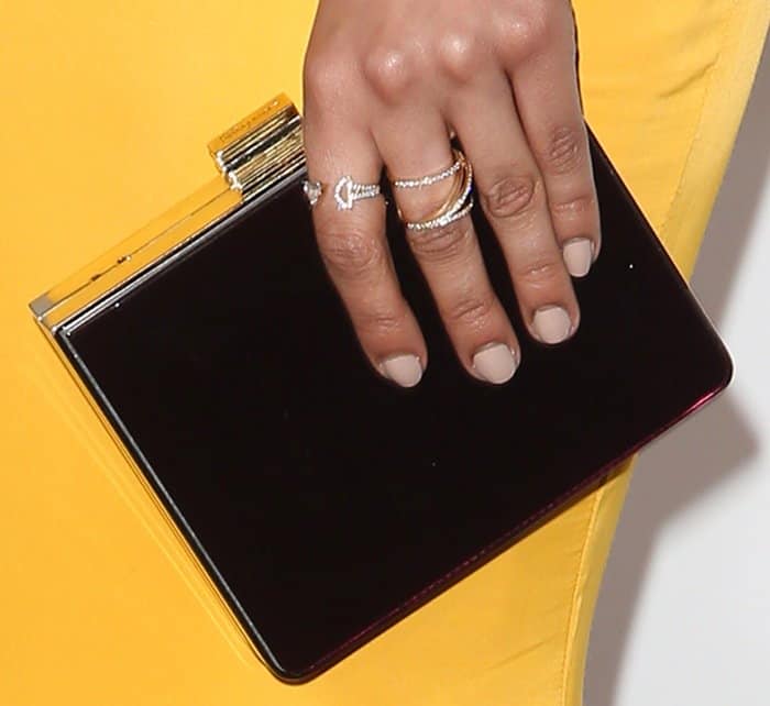 Nathalie Emmanuel accessorized her outfit with a sleek black clutch featuring gold accents and wore multiple delicate, sparkling rings, adding a touch of elegance and sophistication to her ensemble