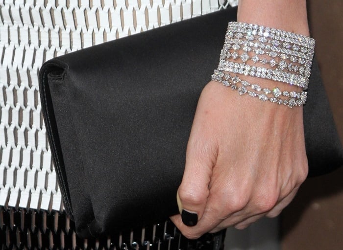 Charlize Theron showing off a black clutch and glittering Harry Winston bracelets