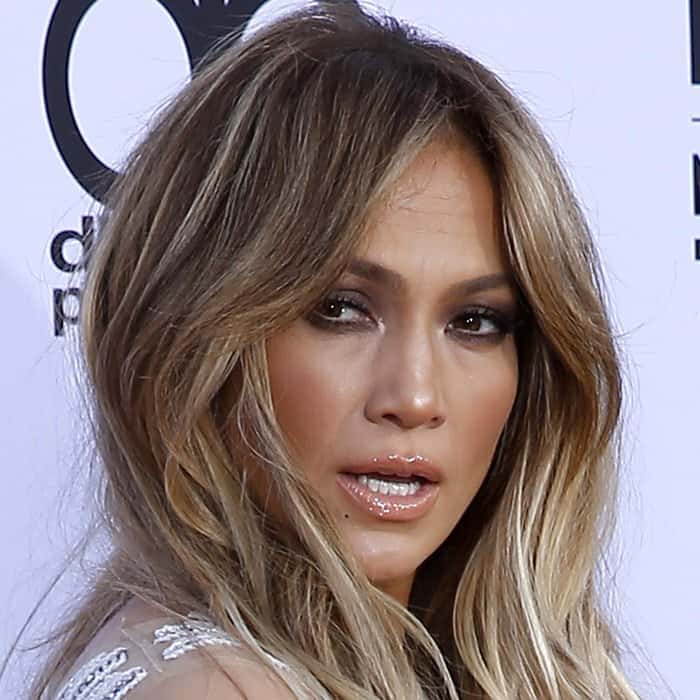 Jennifer Lopez exudes a confident and sultry look with her wavy blonde hair cascading around her face, perfectly complementing her glossy lips and striking eyes