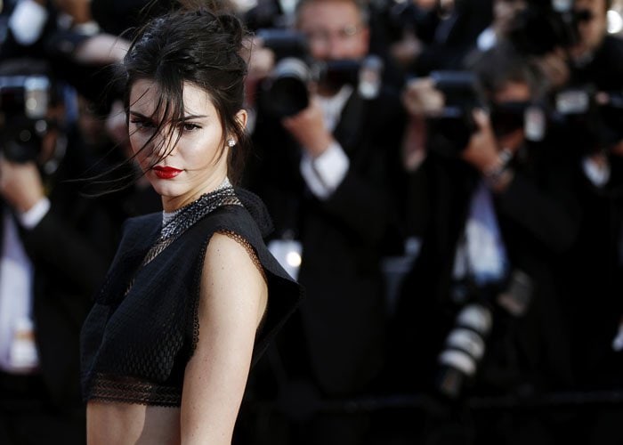 Kendall Jenner stuns in a cropped black top and bold red lipstick at the Cannes Film Festival, capturing the attention of photographers on the red carpet