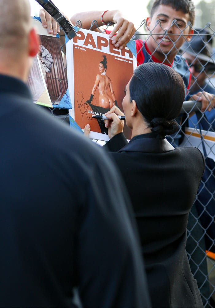 Kim Kardashian signs a copy of her new Paper magazine cover