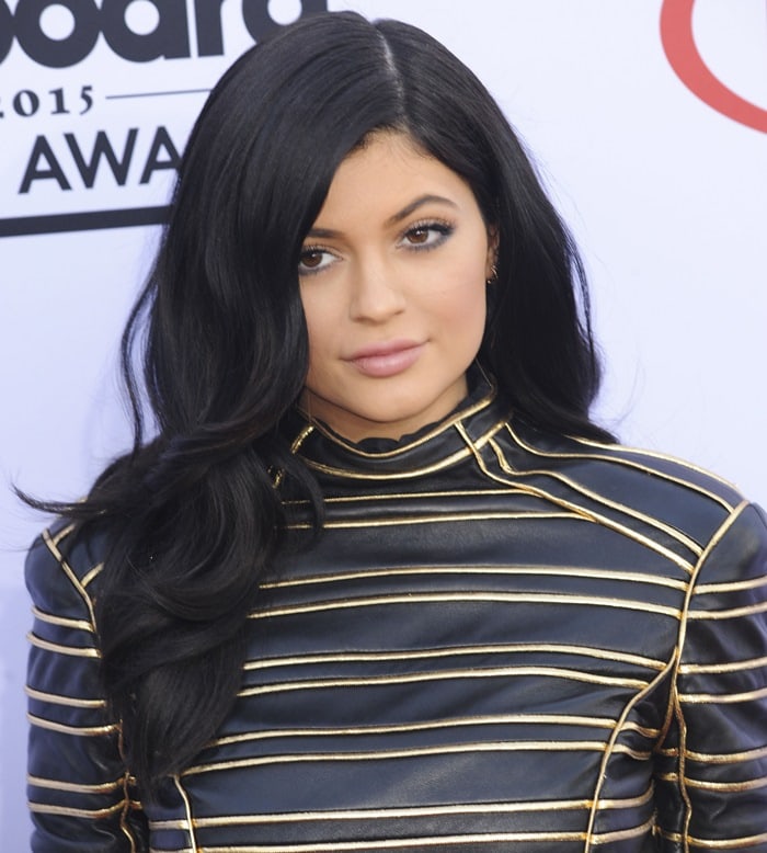 Kylie Jenner stuns with soft waves cascading over her shoulders and natural makeup, perfectly complementing her edgy Balmain leather mini dress