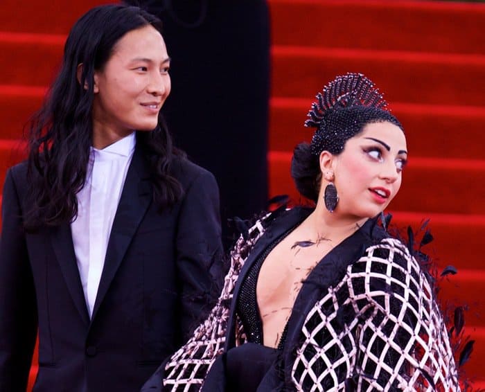 Lady Gaga stuns in a kimono-inspired Balenciaga ensemble with a dramatic bejeweled headpiece and intricate makeup, accompanied by designer Alexander Wang at the 2015 Met Gala