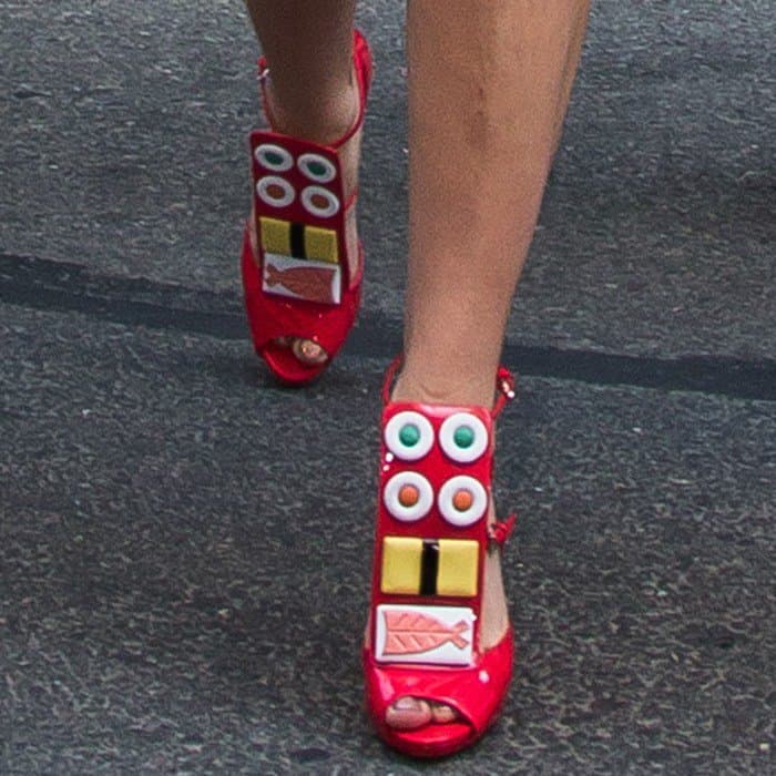 Lady Gaga's shoes are vibrant red platform heels adorned with colorful sushi-themed embellishments