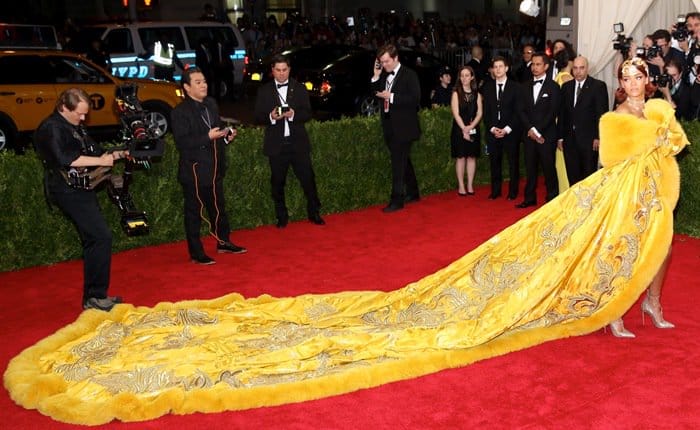 Rihanna steals the spotlight at the 2015 Met Gala in a magnificent yellow Guo Pei gown, featuring an elaborate fur-trimmed train that captivates the audience