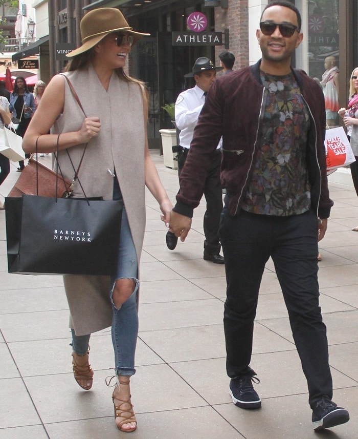Chrissy Teigen rocked a wide-brimmed hat with a sleeveless trench coat and ripped jeans