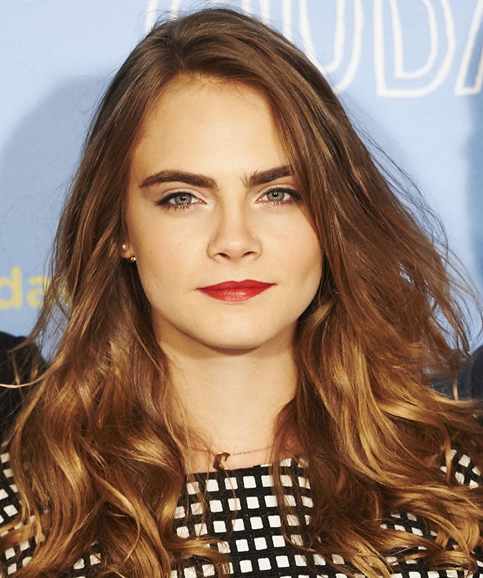 Cara Delevingne shows off her loose brown curls, red pout and simple jewelry look