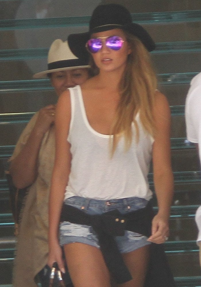 Chrissy Teigen wears denim cutoffs with a plain white tank top