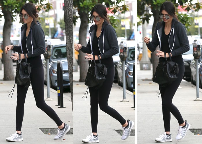 Kendall Jenner looked like she had just been working out in a pair of black tights and a tank top from American Apparel, which she wore under a black zip up hooded jacket