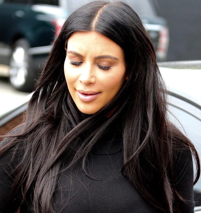 Kim Kardashian keeps it sleek and polished in a classic black turtleneck dress, showcasing her signature glam beauty look