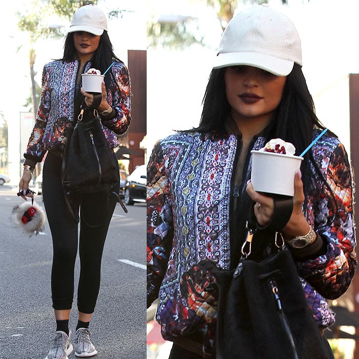 Kylie Jenner wears a quilted printed bomber jacket while carrying a cup of yogurt