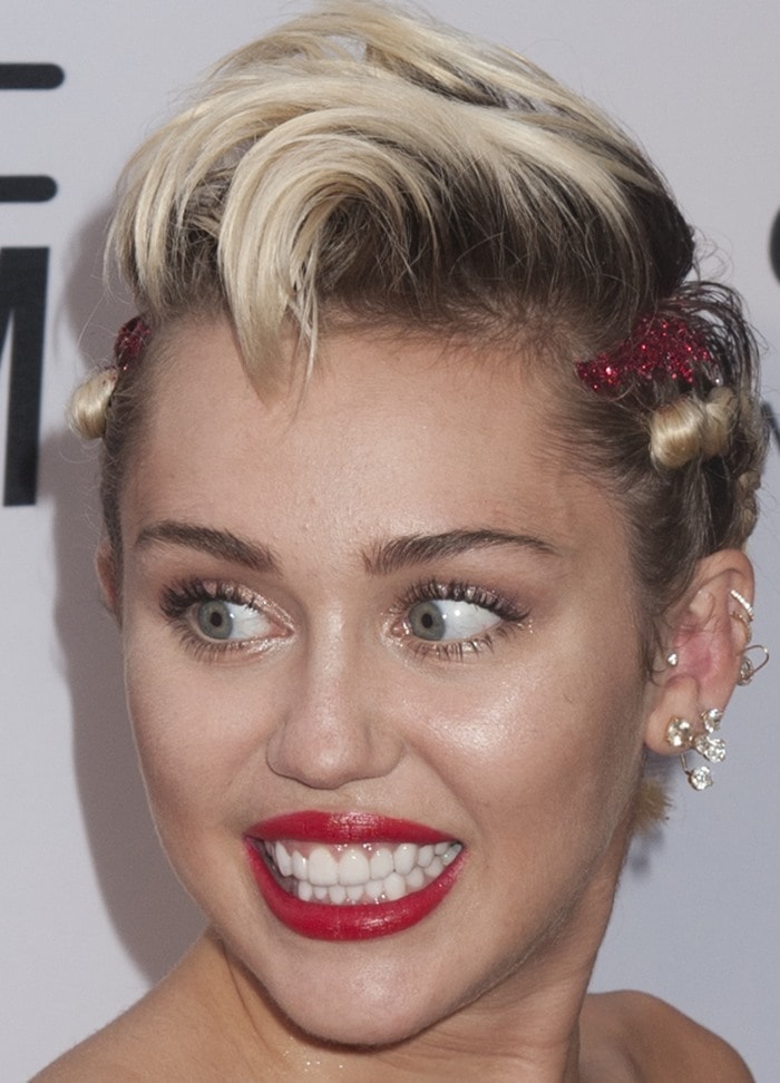 Miley Cyrus shows off her braided blonde hair, red lipstick, and an earful of jewelry