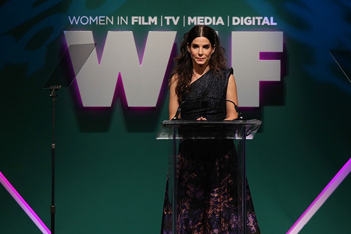 Sandra Bullock stands at a podium at the Women in Film 2015 Crystal + Lucy Awards