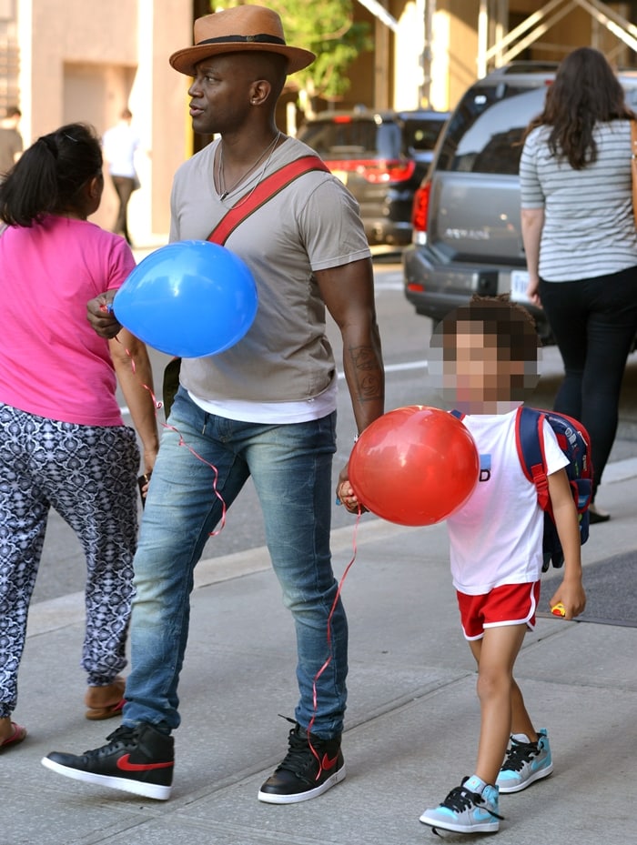 Taye Diggs keeps it stylish and relaxed in skinny jeans, a tan V-neck tee, and black-and-red Nike high-top sneakers while enjoying a balloon-filled walk with his son