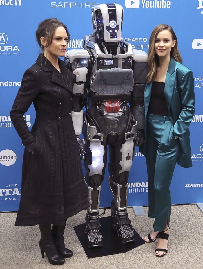 Clara Rugaard paired her teal satin suit with strappy black heels, while Hilary Swank styled her black trench coat with sleek platform ankle boots at the I Am Mother Sundance premiere