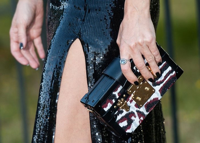 Kate Hudson shows off the detailing on her chic Louis Vuitton clutch, which perfectly matched her dark manicured nails