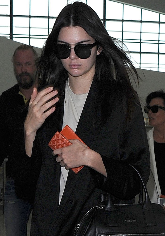 Kendall Jenner dodges cameras as she arrives at Heathrow Airport with her mother, Kris Jenner, on July 14, 2015 following a short stay in London