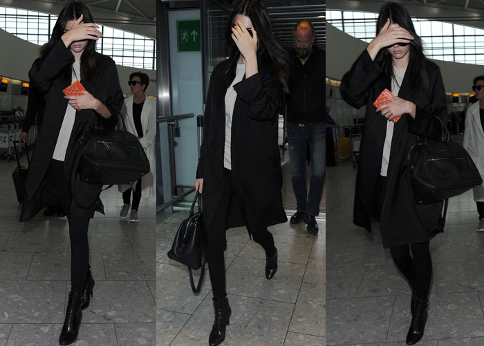 Kendall Jenner shields her sunglass-covered eyes from the cameras in an all-black look as she strolls through the airport