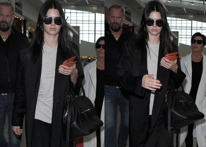 Kendall Jenner ignores the cameras as she strolls through Heathrow Airport in her dark sunglasses and black outfit