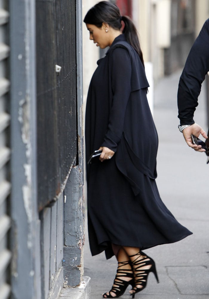 Kim Kardashian stepped out in a figure-hugging color block dress, which she paired with a flowy trenchcoat and her favorite Hermès Impulsion heels in black