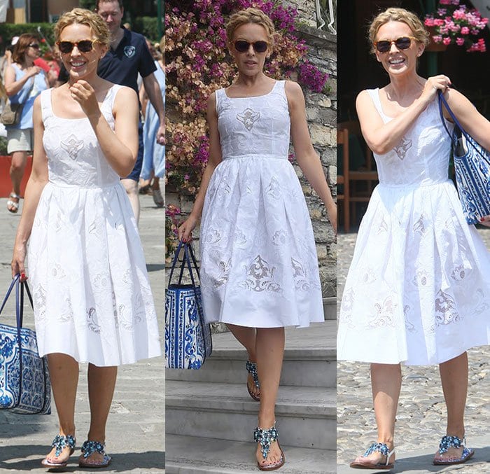 Kylie Minogue is all smiles as she enjoys her holiday in a blue-and-white summery look, complemented by a braided updo and dark sunglasses