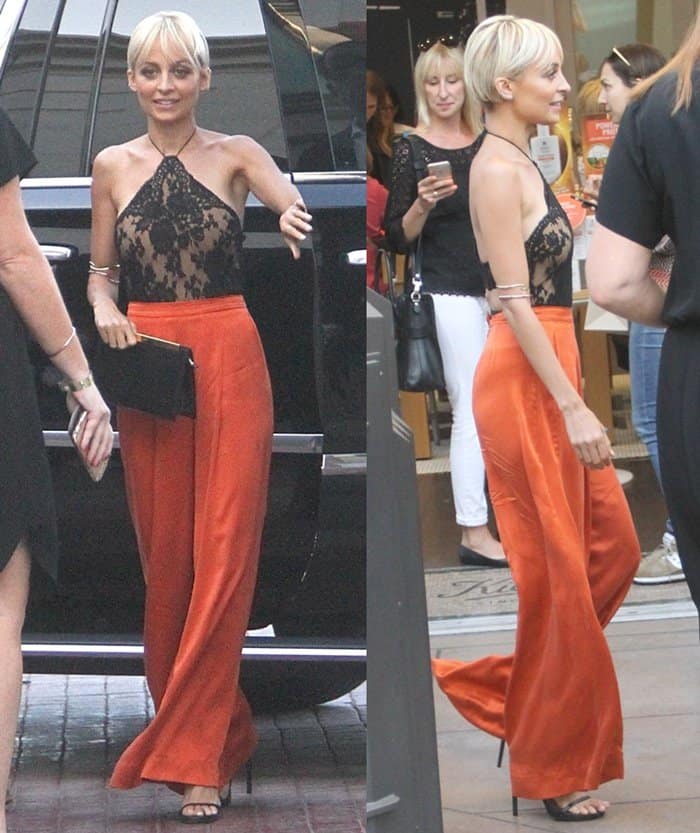 Nicole Richie commands attention in a daring black lace halter top paired with vibrant orange trousers, completing the look with the House of Harlow 1960 gold bangle styled as an edgy arm band