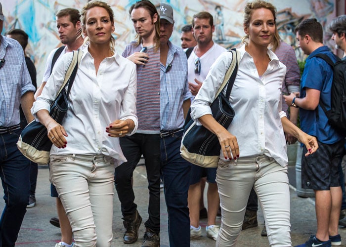 Uma Thurman carries a large navy tote bag with her all-neutral outfit, comprised of unbelted pants and a hastily-tucked button-up