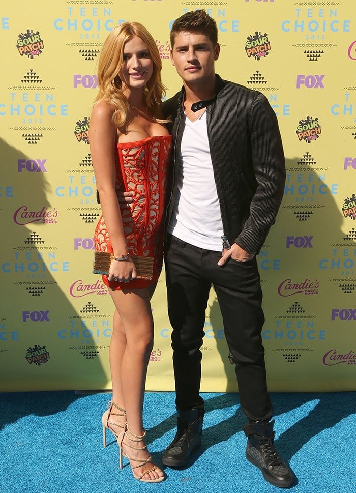 Bella Thorne and Gregg Sulkin pose together at the 2015 Teen Choice Awards, with Bella dazzling in a red strapless mini dress and nude stilettos