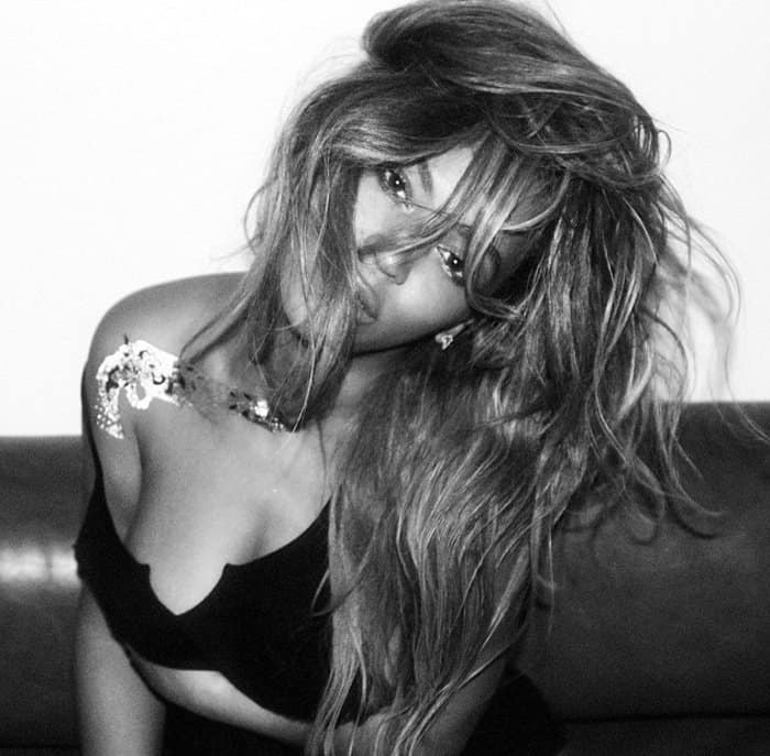 Beyoncé exudes edgy glamour in this black-and-white shot, with tousled hair and a shimmering flash tattoo accentuating her bold, captivating look