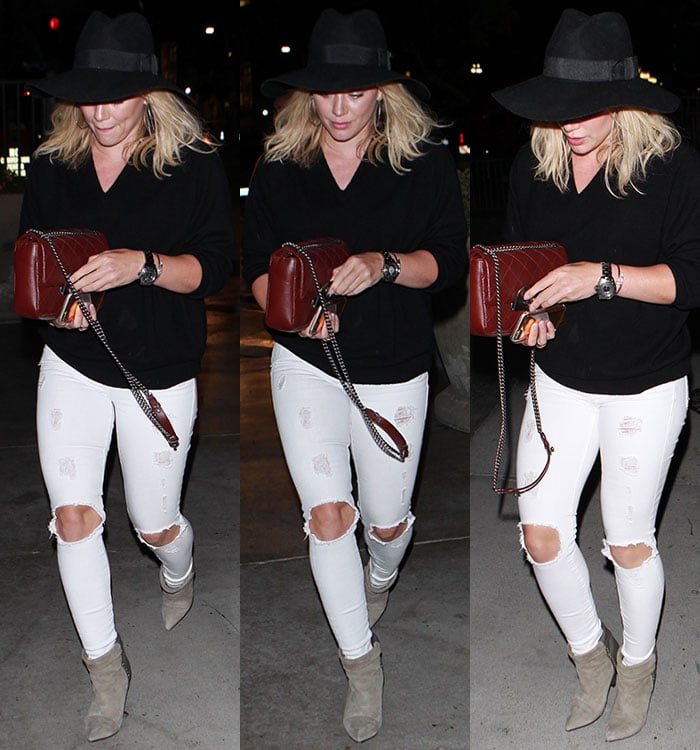 Hilary Duff's blonde tresses peek out from beneath her black hat