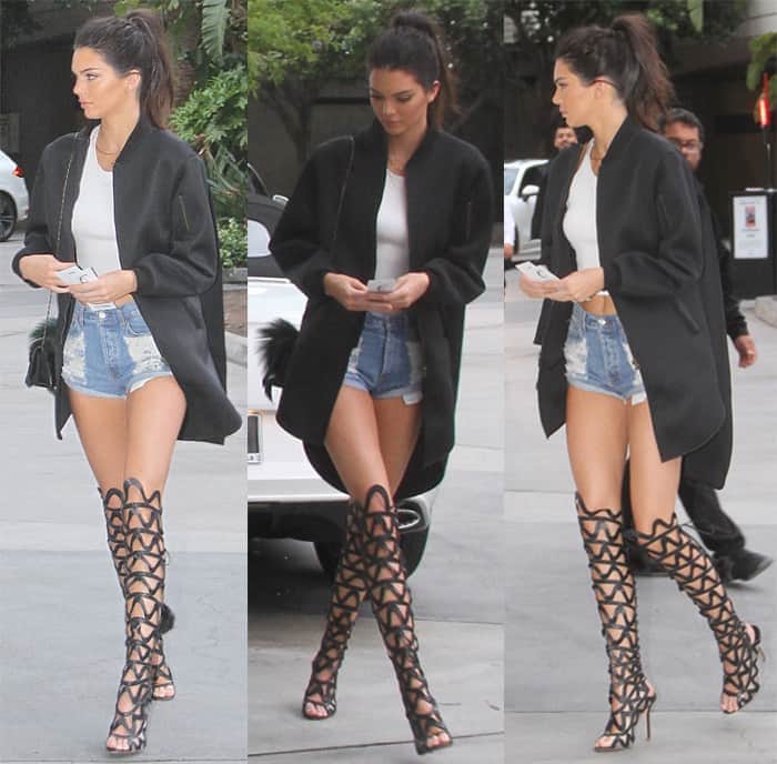 Kendall Jenner experiments with high-waisted shorts, cropped tank, and thigh-high boots under an oversized bomber