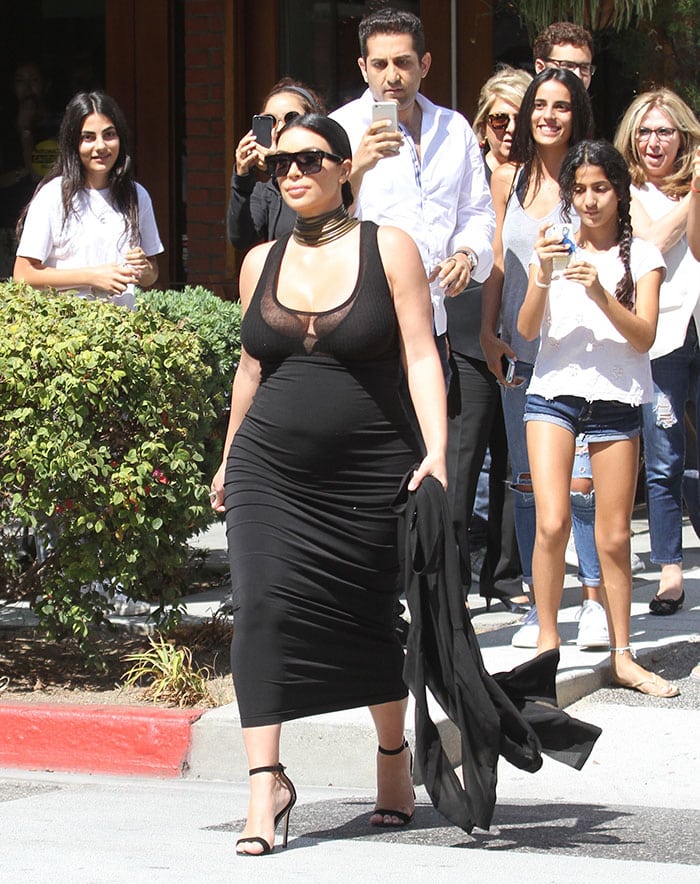 Kim Kardashian effortlessly flaunts her chic maternity style in a form-fitting black dress and classic Manolo Blahnik 'Chaos' sandals while out with friends in Beverly Hills