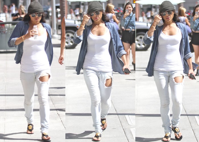 Michelle Rodriguez pairs a white tank top and white ripped jeans with an unbuttoned shirt for her casual stroll