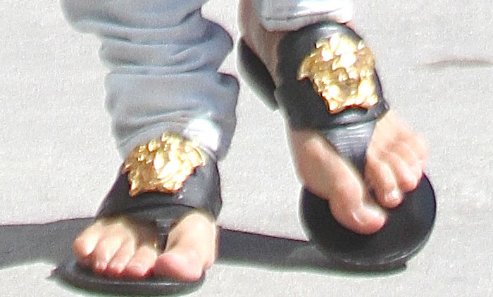 Michelle Rodriguez lets the hem of her white pants slouch around the tops of her Versace sandals.