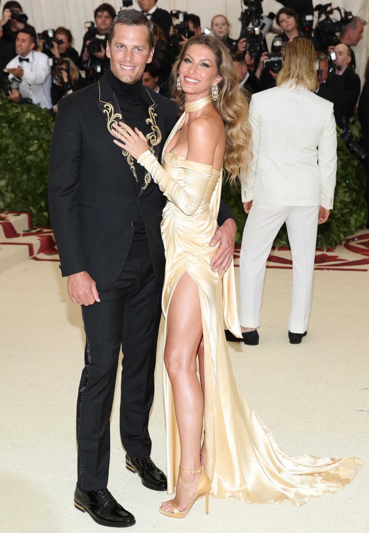 Gisele Bündchen in an eco-friendly long, gold Versace dress with Tom Brady in an embellished tuxedo at the 2018 Met Gala