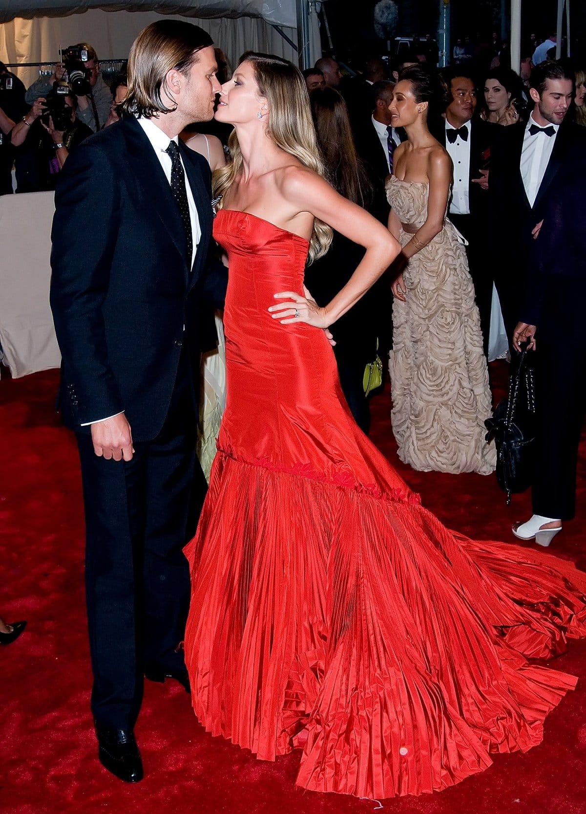 Gisele Bündchen in a red strapless Alexander McQueen Fall 2005 red fish-tail dress kissing Tom Brady at the 2011 Met Gala