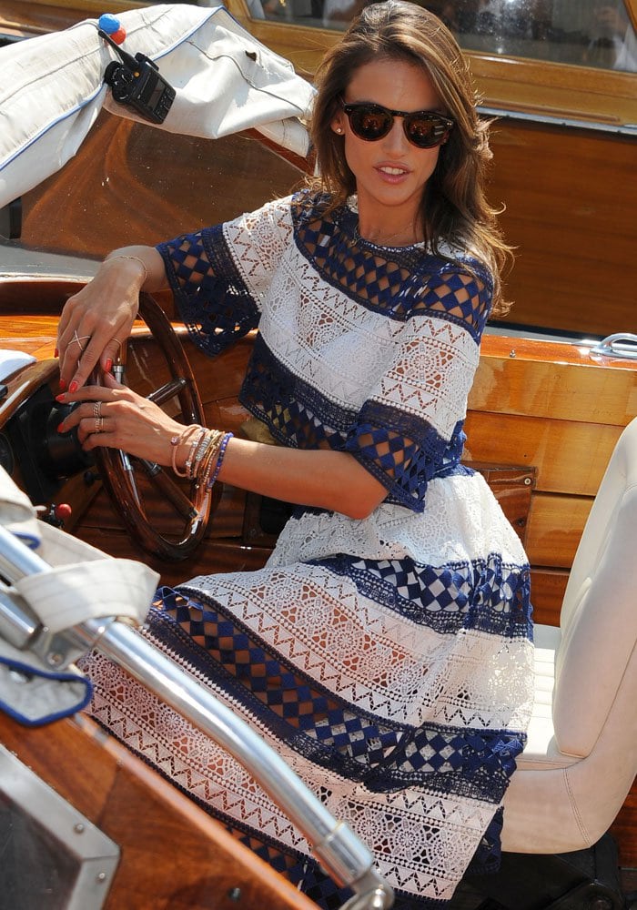 Alessandra Ambrosio poses in a boat as she shows off her colorful manicure and stacks of bracelets