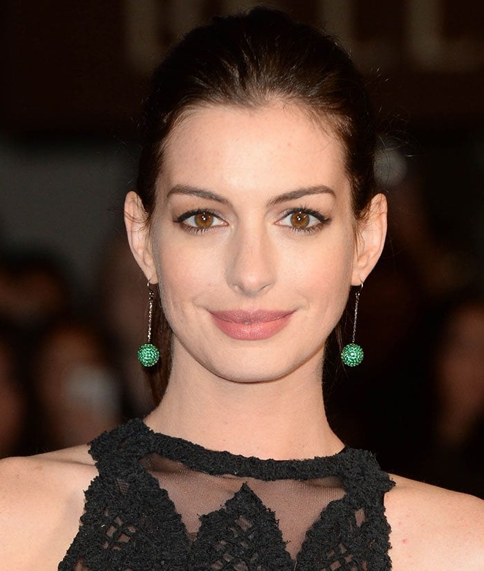 Anne Hathaway wears her hair back in a classy ponytail and accentuates her look with colorful Solange Azagury-Partridge emerald drop earrings