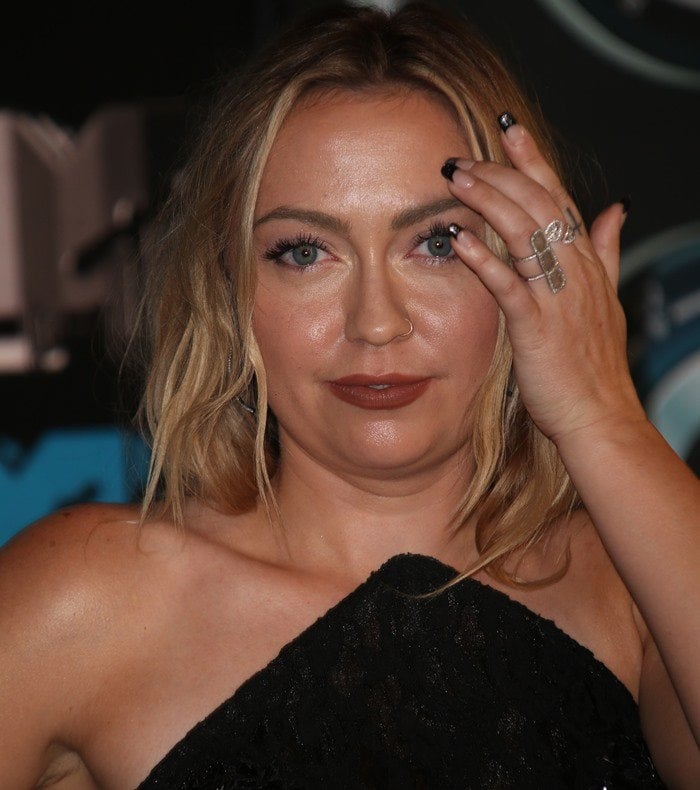 Brandi Cyrus brushes her messy blonde hair out of her face as she poses for a photo