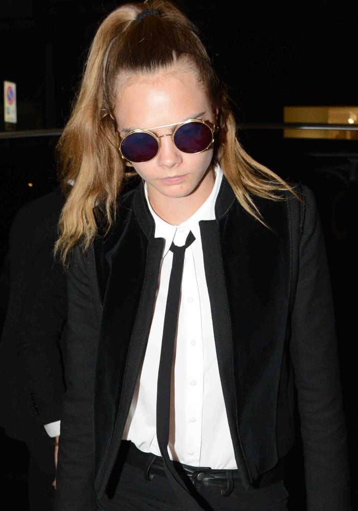 Cara Delevingne put her hair up in a ponytail and hid her eyes behind round lens sunglasses