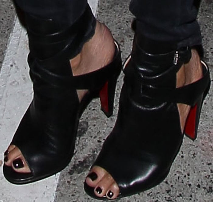 Chrissy Teigen coordinates her black pedicure with edgy Christian Louboutin Hippik peep-toe booties, featuring bold cutouts and signature red soles