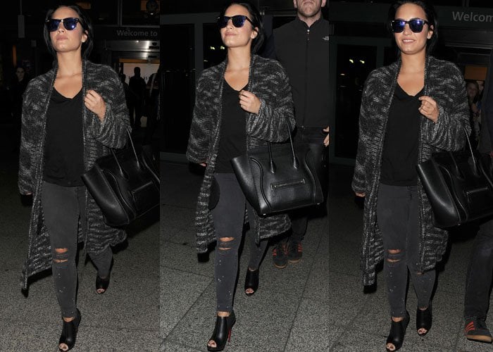 Demi Lovato sports a black-and-gray outfit as she juggles a tote and strolls through London's airport