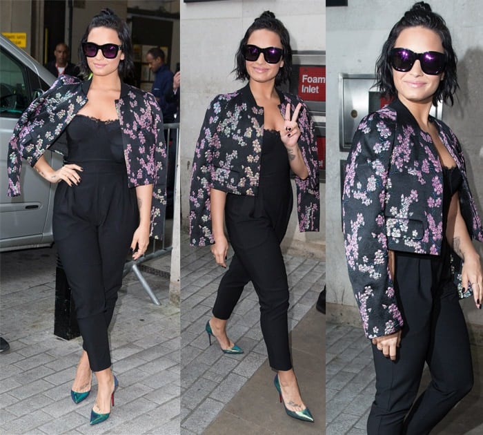 In London on September 9, 2015, Demi Lovato elegantly paired a Dries Van Noten Bangalore floral-brocade jacket with a House of CB Pietrina lace strapless bustier jumpsuit, accessorized with Christian Louboutin Iriza pumps and Illesteva Hamilton black and pink mirrored sunglasses
