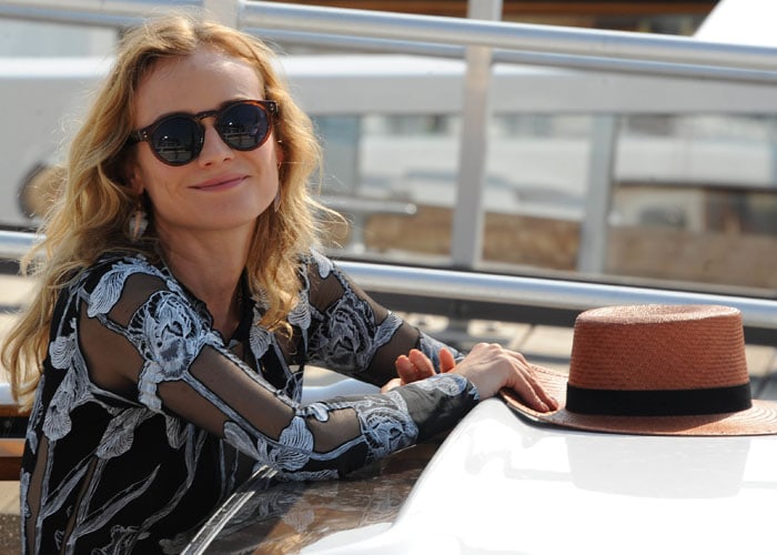 Diane Kruger shows off her Komono sunglasses and her Janessa Leone straw hat as she poses for photos