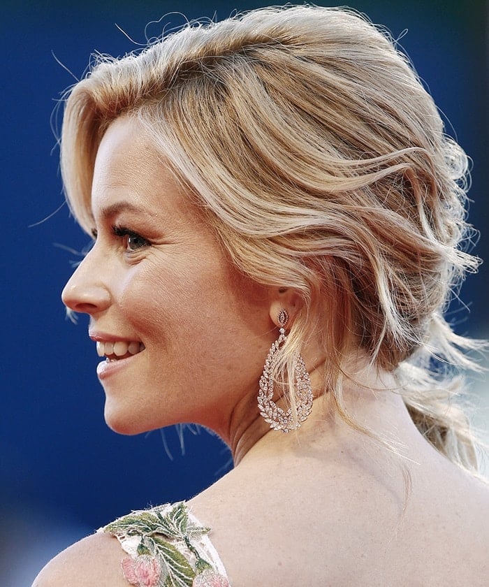 Elizabeth Banks turns her head to the side to flaunt her wavy blonde updo and shining silver earrings